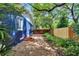 Side yard view of the property shows a quaint walkway leading to a private, fenced yard and lush landscaping at 6110 N Suwanee Ave, Tampa, FL 33604