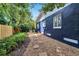 The backyard with a path around the house showcases the home's unique exterior paint and lush landscaping at 6110 N Suwanee Ave, Tampa, FL 33604
