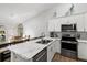 Bright kitchen with stainless steel appliances, white cabinetry, and marble countertops. Dining area viewable through a large window at 6420 92Nd N Pl # 1205, Pinellas Park, FL 33782