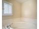 Corner bathtub with white tile surround next to a window with white shutters at 6980 Ulmerton Rd # 7C, Largo, FL 33771