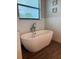 Modern bathroom features a freestanding soaking tub, white subway tile, and beautiful wood-look flooring at 7307 S Morton St, Tampa, FL 33616