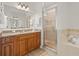 Well-lit bathroom featuring a glass shower, soaking tub, granite countertop vanity and wood cabinetry at 7612 S 36Th Ave, Tampa, FL 33619