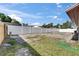 A long, white vinyl fence encloses a sunny backyard with grass and a garden hose at 811 Pebblewood Dr, Brandon, FL 33511