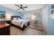 Bright bedroom with wood-look tile flooring, ceiling fan, wooden bed frame, and blue painted walls at 868 Bayway Blvd # 206, Clearwater Beach, FL 33767