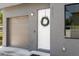 Close-up of a gray townhouse entrance featuring a garage, white door, and minimalist wreath at 8723 Palm Ranches Pl, Tampa, FL 33614