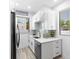 Compact kitchenette with white cabinets, stainless steel appliances, quartz countertops, and bright windows at 8723 Palm Ranches Pl, Tampa, FL 33614