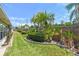 Beautifully landscaped backyard featuring lush green grass, trimmed hedges, and mature palm trees in a serene setting at 93 Boca Ciega Point N Blvd # 93, St Petersburg, FL 33708