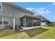 Exterior shot of a screened-in patio, green lawn, and house exterior on a sunny day at 9665 Sweetwell Pl, Riverview, FL 33569