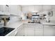 Bright kitchen features white cabinetry, countertops and appliances with a view to the living room at 9815 Harrell Ave # 503, Treasure Island, FL 33706