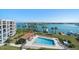 Community pool with stunning water views, palm trees, lounge seating, and a nearby cabana at 9815 Harrell Ave # 503, Treasure Island, FL 33706