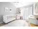 Bright Bedroom with modern crib, comfortable armchair, patterned rug, and white curtains at 10357 Lightner Bridge Dr, Tampa, FL 33626