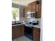 Well-lit kitchen with stainless steel appliances, mosaic backsplash, and stained wood cabinets at 11351 Edison Ave, New Port Richey, FL 34654