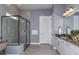 A modern bathroom features a glass-enclosed shower, granite vanity with double sinks, and stylish lighting at 11443 Shoreline Trl, Parrish, FL 34219