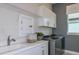 Bright laundry room with white cabinets, stainless steel washer and dryer, and a utility sink at 11443 Shoreline Trl, Parrish, FL 34219