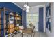 Bright home office with a blue accent wall, built-in shelving, and a cozy workspace with natural light at 11443 Shoreline Trl, Parrish, FL 34219