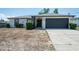 Charming single-story home featuring a well-maintained lawn and a dark gray garage door at 12456 Spreading Oak Dr, Spring Hill, FL 34609