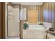 Bathroom featuring a glass enclosed shower, a garden tub, and tan tiled walls at 13813 Sigler St, Riverview, FL 33579