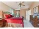 Spacious bedroom with large dresser, ceiling fan, warm paint, and king-size bed with a red bedspread at 13813 Sigler St, Riverview, FL 33579