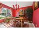 Dining room with red walls, wooden furniture, bright windows, and red accents at 13813 Sigler St, Riverview, FL 33579