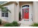 Charming front entrance with a vibrant red door, decorative wreath, and welcome sign at 13813 Sigler St, Riverview, FL 33579