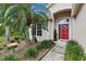 Beautifully landscaped front entrance with a vibrant red door and decorative wreath, creating a welcoming curb appeal at 13813 Sigler St, Riverview, FL 33579