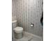 Cozy bathroom featuring a standard toilet, floral wallpaper, and classic marble flooring at 19029 Us Highway 19 N # 2-23, Clearwater, FL 33764