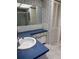 Bathroom featuring blue vanity, white marble-look flooring, and large mirror at 19029 Us Highway 19 N # 2-23, Clearwater, FL 33764
