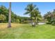 Serene backyard with mature palm trees, lush grass, and a tranquil pond view at 19107 Avenue Bayonnes, Lutz, FL 33558