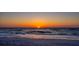 Vibrant sunset over the ocean with gentle waves and a sandy beach in the foreground at 19530 Gulf Blvd # 4A, Indian Shores, FL 33785