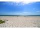 Sandy beach view with gentle waves in the background under a sunny blue sky at 19530 Gulf Blvd # 4A, Indian Shores, FL 33785