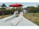 Relaxing lounge chairs sit poolside beneath a red umbrella, offering a shady retreat at 1980 Forked Creek Dr, Englewood, FL 34223
