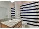 Bathroom featuring a marble vanity and sink, toilet, and tub with navy and white striped curtain at 2220 Elizabeth Way, Dunedin, FL 34698
