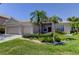 Inviting single-story house featuring a two-car garage, lush landscaping, and a well-maintained lawn at 2220 Elizabeth Way, Dunedin, FL 34698