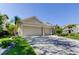 A two-car garage boasts an expansive driveway and lush landscaping, nestled in a vibrant neighborhood at 2220 Elizabeth Way, Dunedin, FL 34698