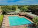 Aerial view of a pool with lounge chairs, a covered area, and parking in a lovely neighborhood at 27012 Sea Breeze Way, Wesley Chapel, FL 33544