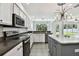 Open kitchen with stainless steel appliances, gray cabinets, tile floors, and natural light overlooking the backyard at 27012 Sea Breeze Way, Wesley Chapel, FL 33544