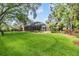 Expansive backyard boasts a lush lawn, manicured landscaping, a screened pool, and an elegant pergola at 2769 St Andrews Blvd, Tarpon Springs, FL 34688
