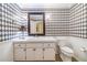 Unique bathroom with diamond patterned walls, vanity with a lamp, and a toilet at 2769 St Andrews Blvd, Tarpon Springs, FL 34688