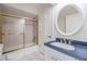 Bright bathroom features a bathtub with gold-trimmed sliding glass doors and a blue vanity at 2769 St Andrews Blvd, Tarpon Springs, FL 34688