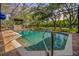 Inviting screened-in pool area with brick pavers and a tranquil setting surrounded by trees at 2769 St Andrews Blvd, Tarpon Springs, FL 34688