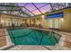 Screened-in pool with brick surround and yellow house with blue awnings, creating an inviting backyard oasis at 2769 St Andrews Blvd, Tarpon Springs, FL 34688