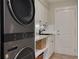 Well-organized laundry room showcasing stacked washer and dryer with a sink and storage at 315 Ridge Rd, Palm Harbor, FL 34683