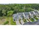 Aerial view of townhomes with garages, lush landscaping, and a pond with a fountain nearby at 3205 Audubon Ct, Tarpon Springs, FL 34688