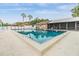 Community pool with lounge chairs, palm trees and community building at 3205 Audubon Ct, Tarpon Springs, FL 34688