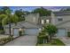 Exterior shot of two-story townhome featuring attached garages, landscaped yard, and neutral color scheme, all under a colorful evening sky at 3205 Audubon Ct, Tarpon Springs, FL 34688