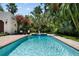 Inviting backyard pool featuring a fountain, brick surround, lush landscaping and palm trees at 3212 W Fountain Blvd, Tampa, FL 33609