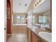 Well-lit bathroom with double sinks, separate tub, and a glass-enclosed shower at 35819 Diamond Head Ct, Zephyrhills, FL 33541