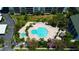 Aerial view of an irregular shaped pool with lounge chairs and tiki umbrellas surrounded by condos and greenery at 400 Island Way # 1709, Clearwater Beach, FL 33767