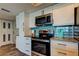 Kitchen features stainless appliances, white cabinetry, tile backsplash, granite countertops and wood-look flooring at 400 Island Way # 1709, Clearwater Beach, FL 33767