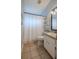 Well-lit bathroom featuring a single sink vanity, neutral tile, and shower with curtain at 412 Henderson Ave, Seffner, FL 33584